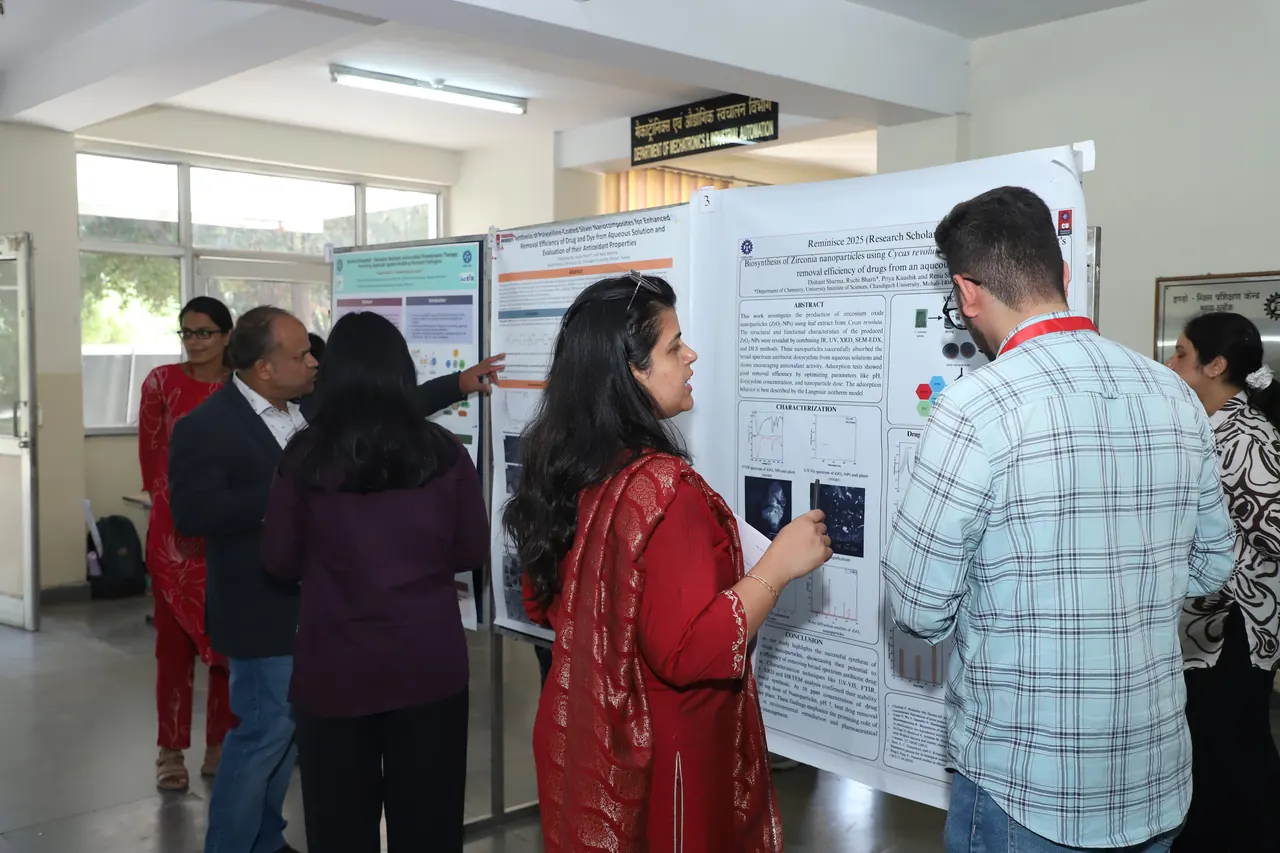 Research scholars and visitors discuss scientific posters at the Reminisce 2025 poster session